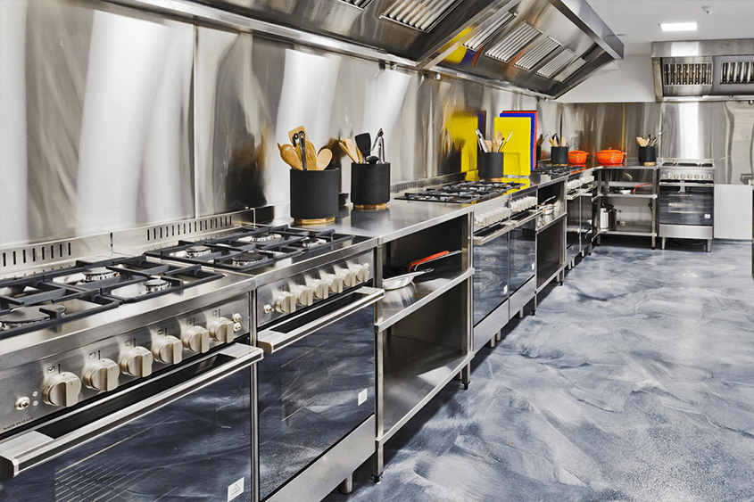 Uma grande cozinha comercial com eletrodomésticos e utensílios de aço inoxidável.