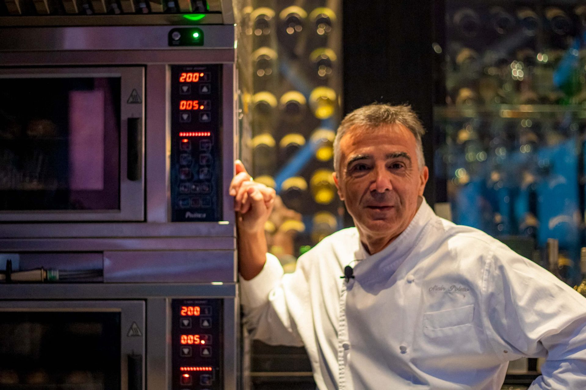 Um homem com uniforme de chef está em frente a um forno de micro-ondas.