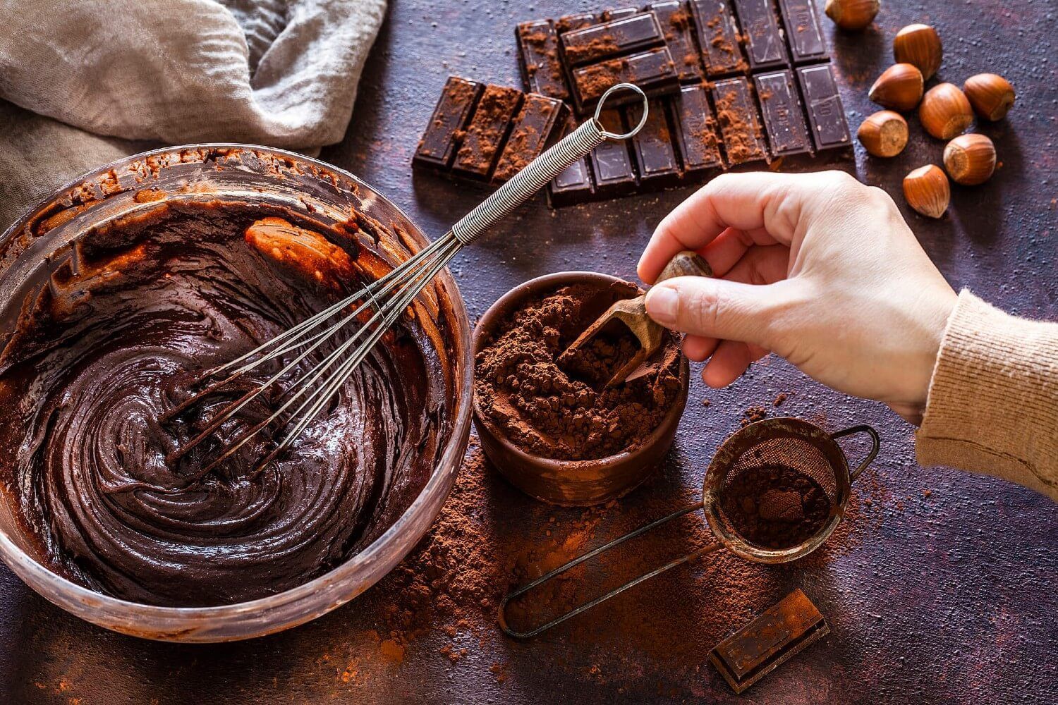 Uma pessoa está misturando chocolate em uma tigela com um batedor.