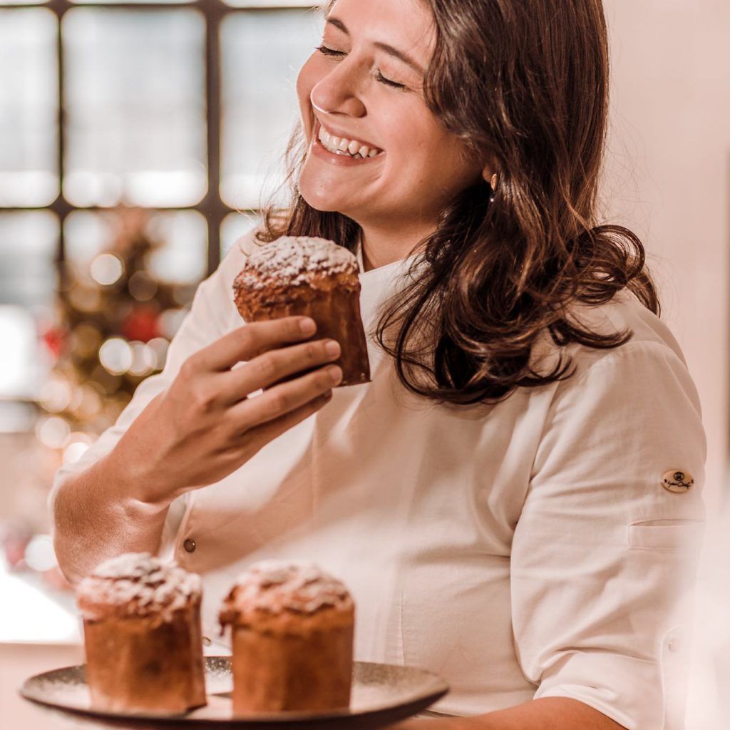 Uma mulher está sorrindo enquanto segura um bolinho na mão