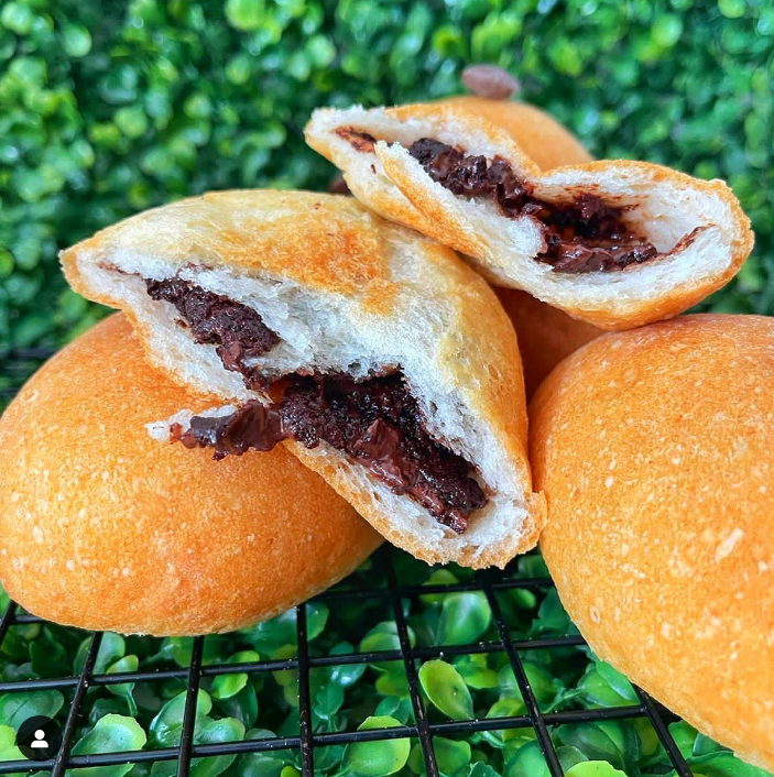 Um close de um pãozinho com uma mordida.