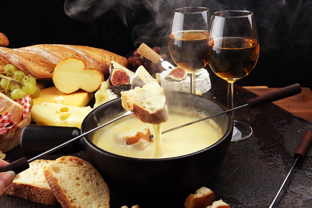 Uma pessoa está mergulhando pão em uma tigela de fondue.