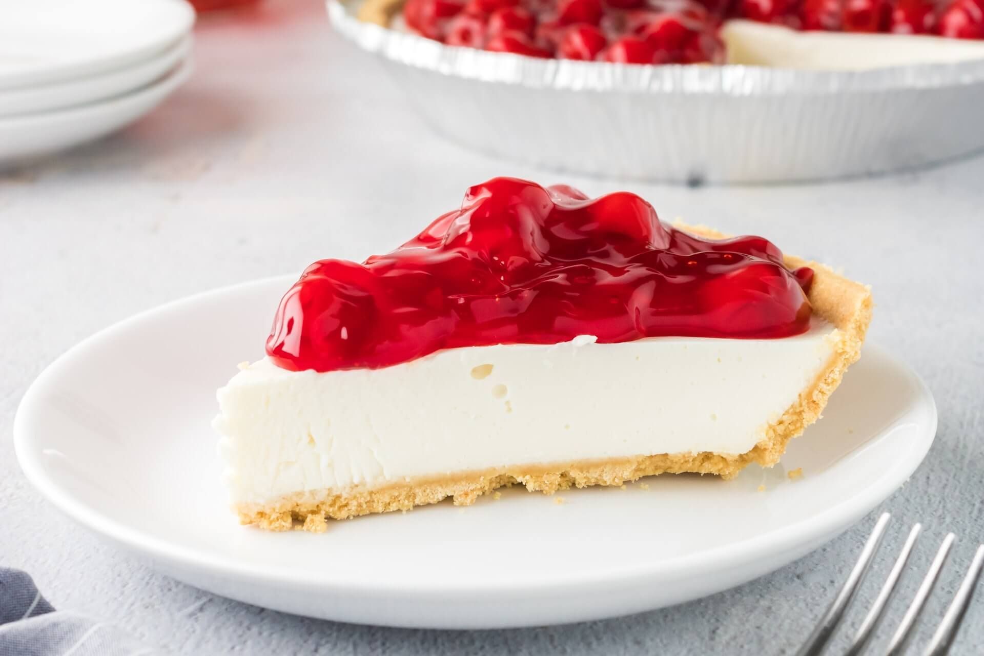 Uma fatia de torta de cereja em um prato branco com um garfo.