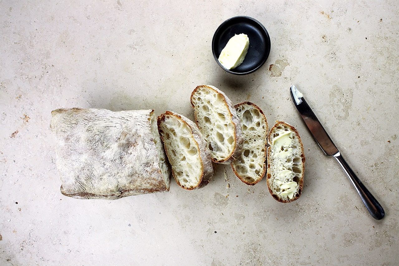 pão italiano ciabatta cortado com manteiga e faca sobre pedra