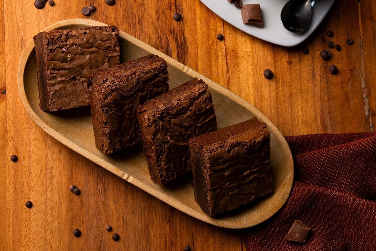 Uma bandeja de madeira cheia de brownies de chocolate sobre uma mesa de madeira.