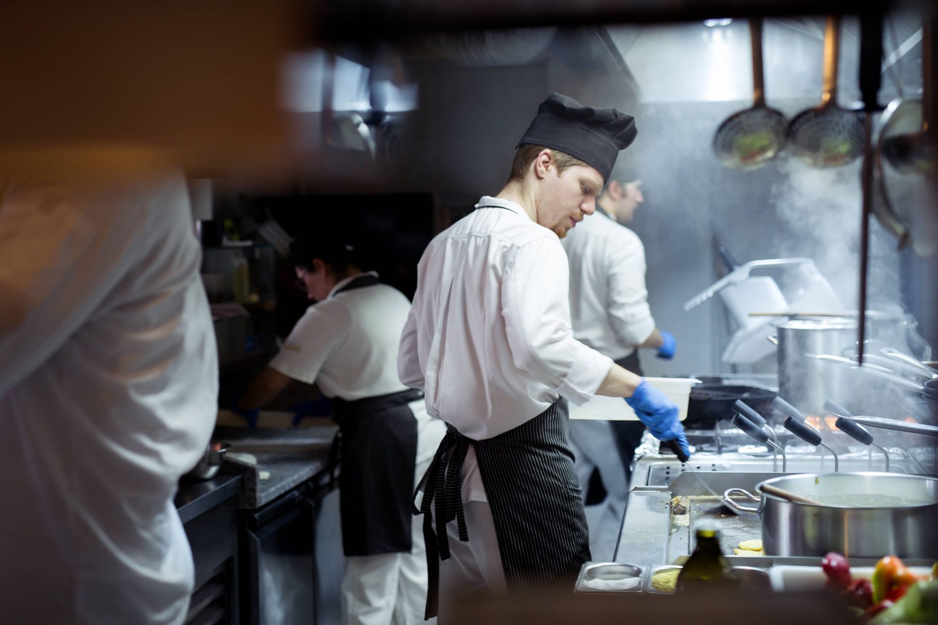 Um grupo de chefs está preparando comida em uma cozinha.