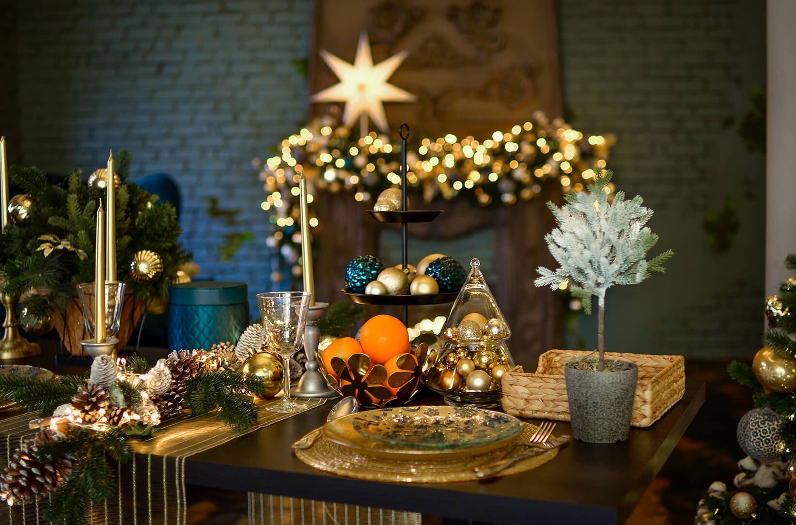 Uma mesa decorada para o natal com pratos, velas, laranjas e árvores.
