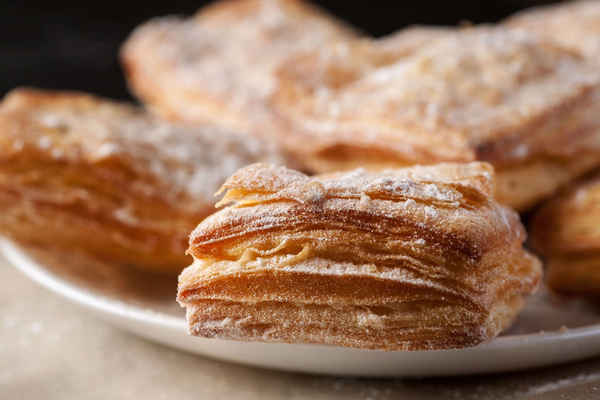 Um close de um pedaço de massa em um prato com açúcar de confeiteiro.