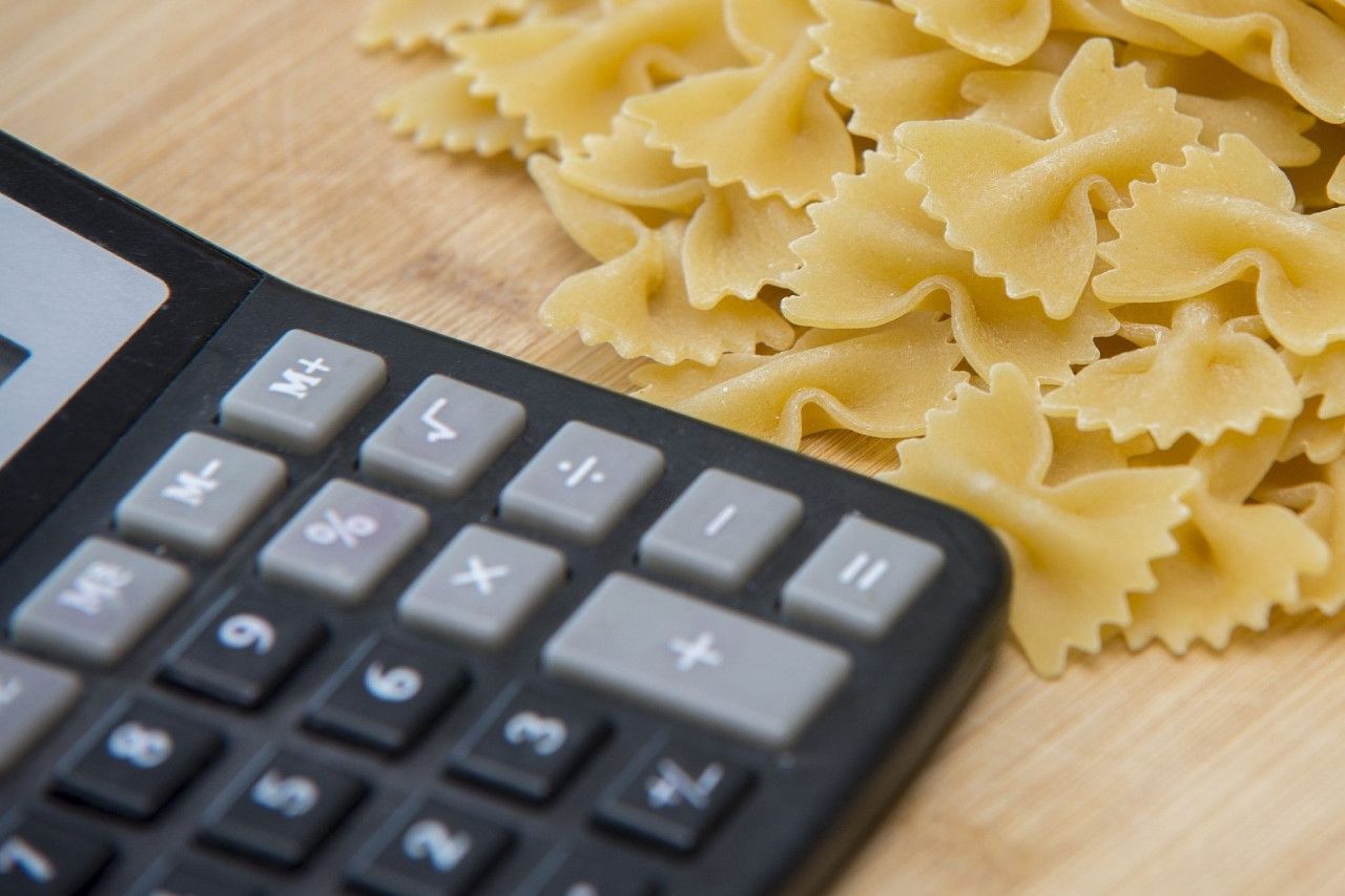 Uma pilha de macarrão ao lado de uma calculadora em uma mesa de madeira.