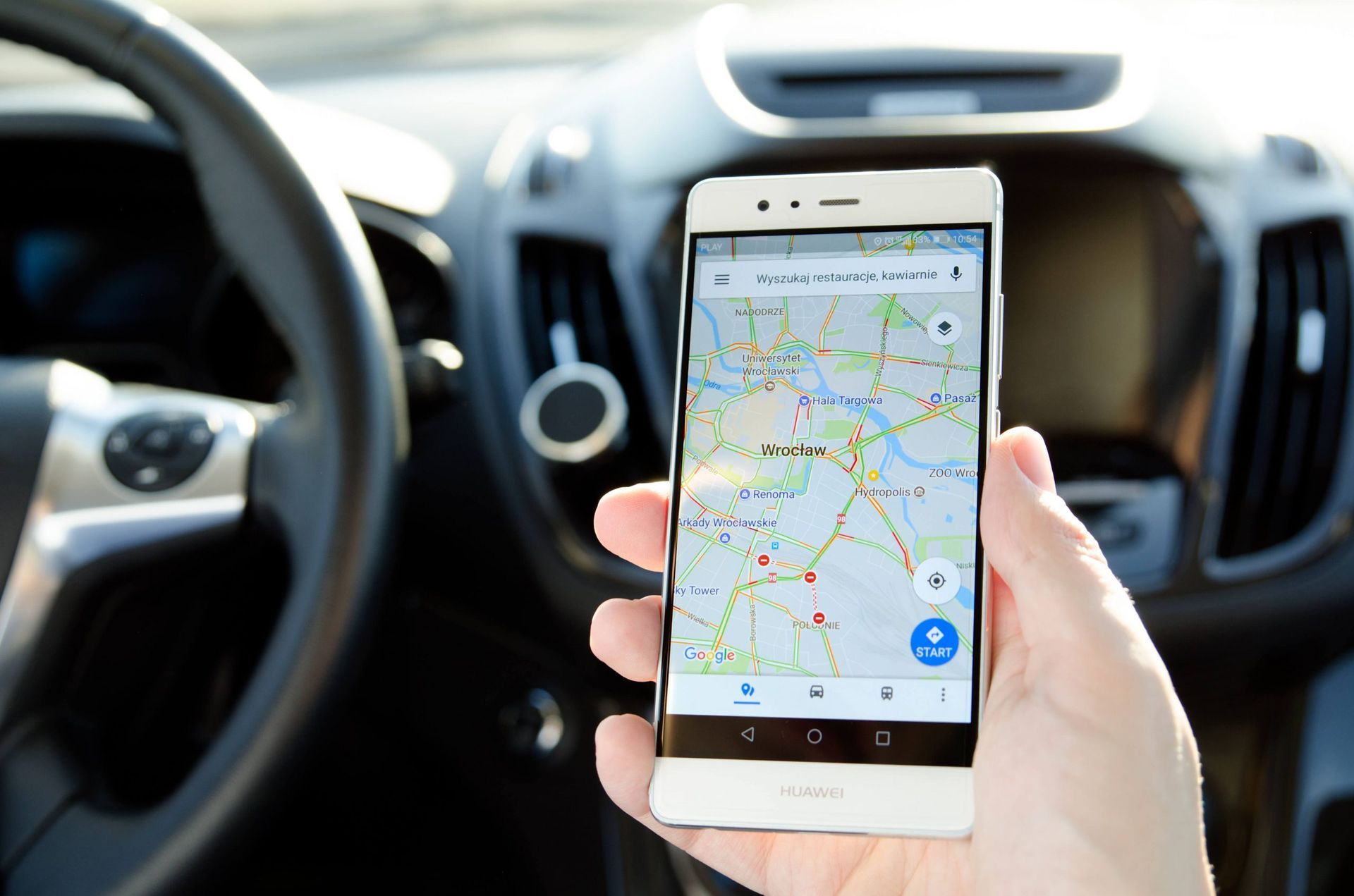 Uma pessoa está segurando um celular na mão dentro de um carro.