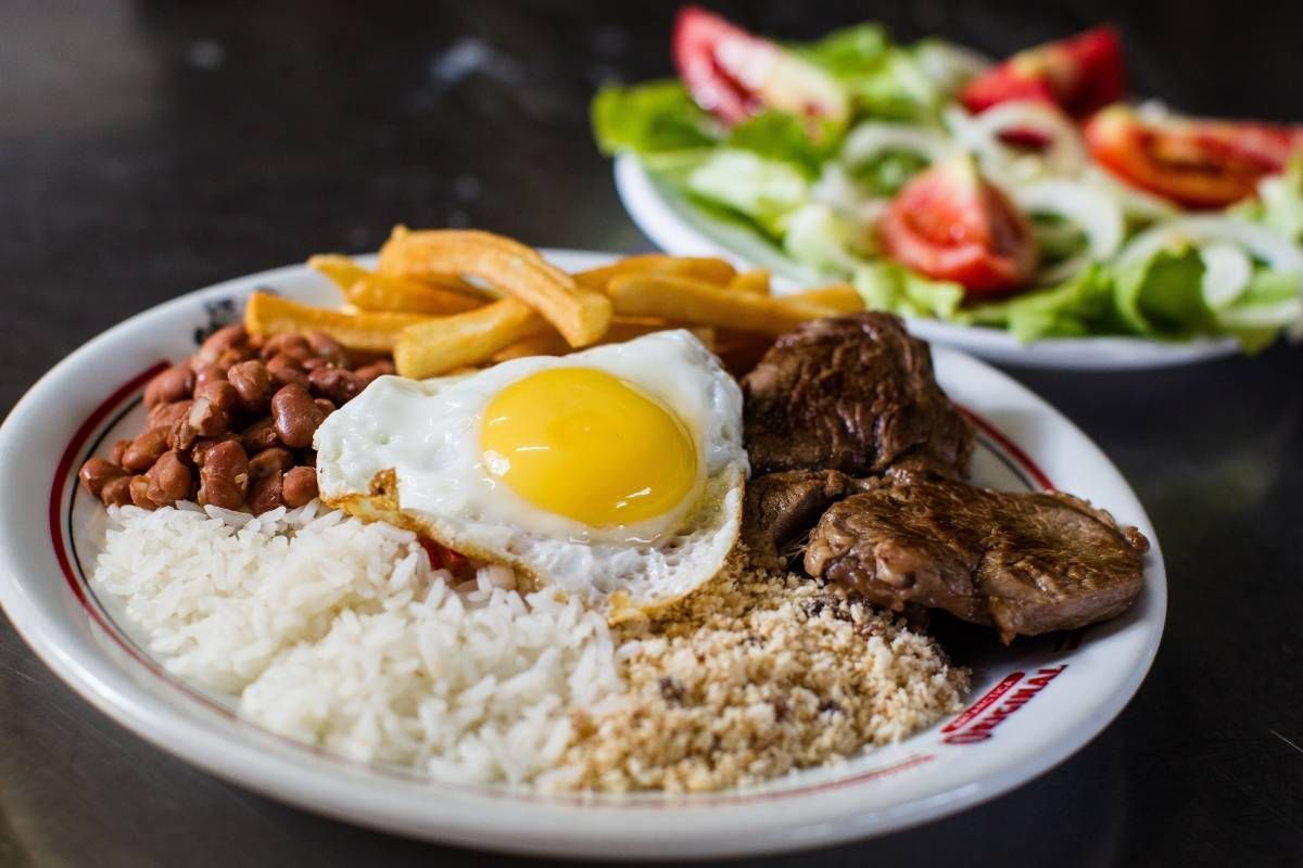Um prato de comida com arroz feijão e um ovo frito