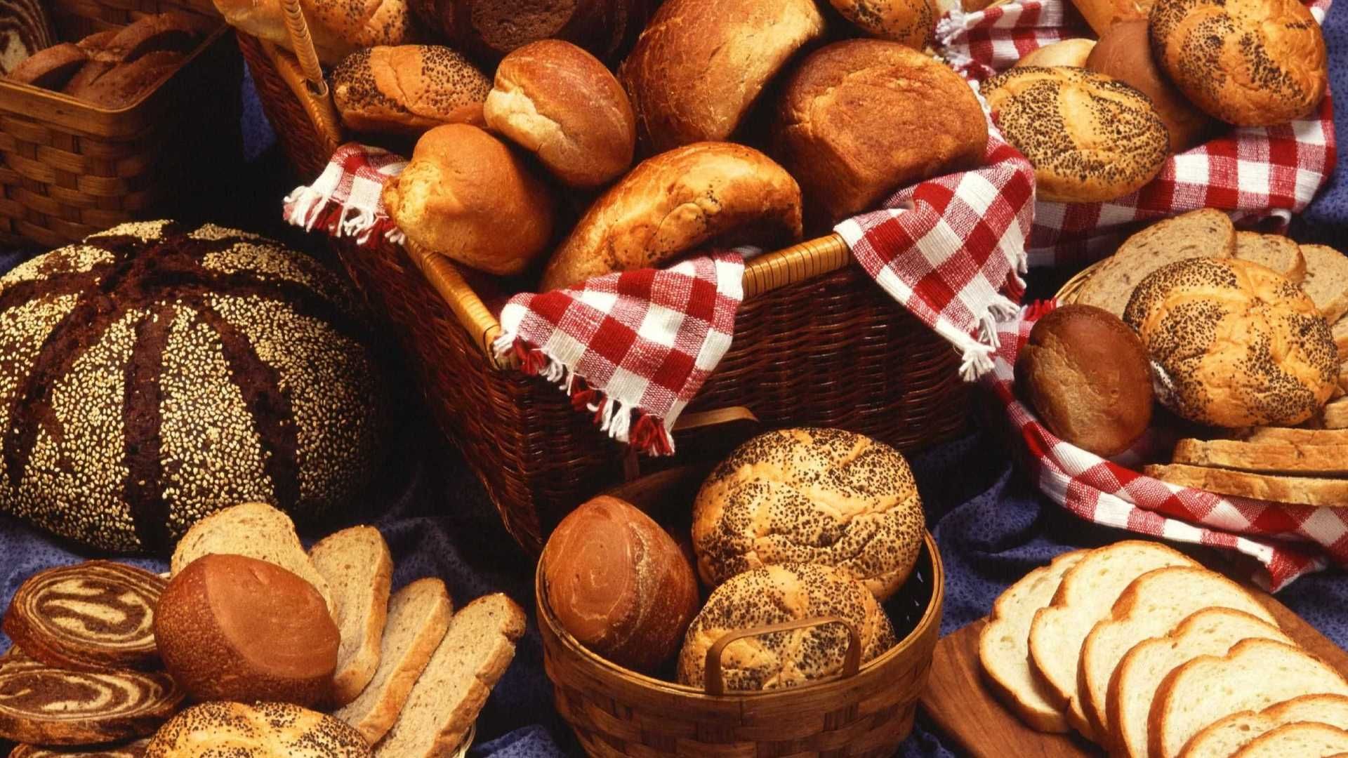 Uma cesta de pães fica sobre uma mesa com outros pães