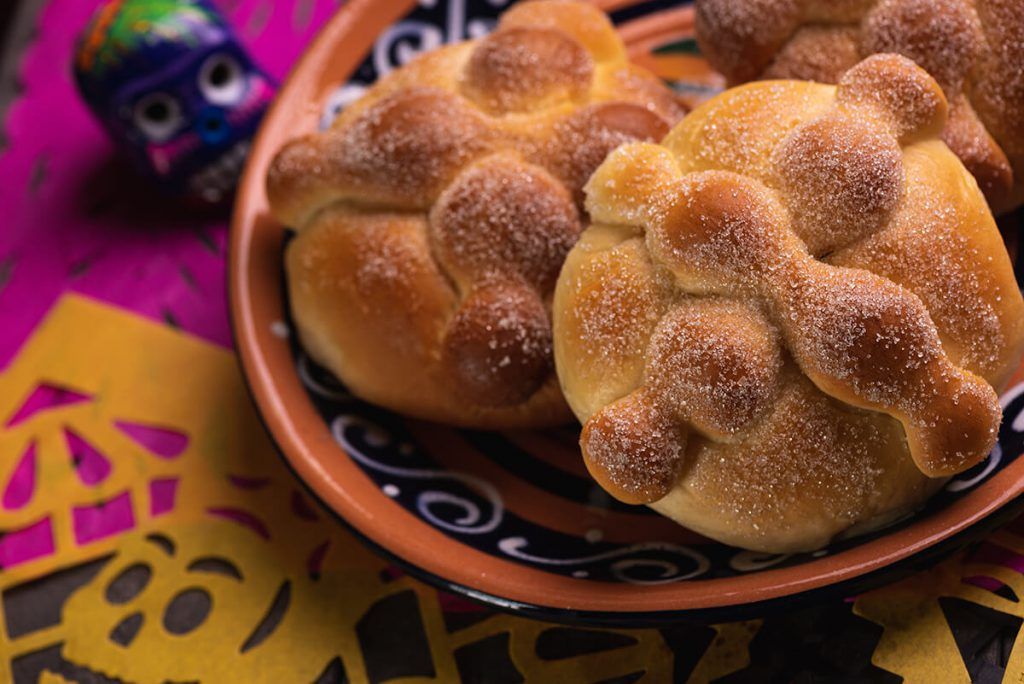 pan de muerto em cerâmica e sobre mesa com toalha colorida
