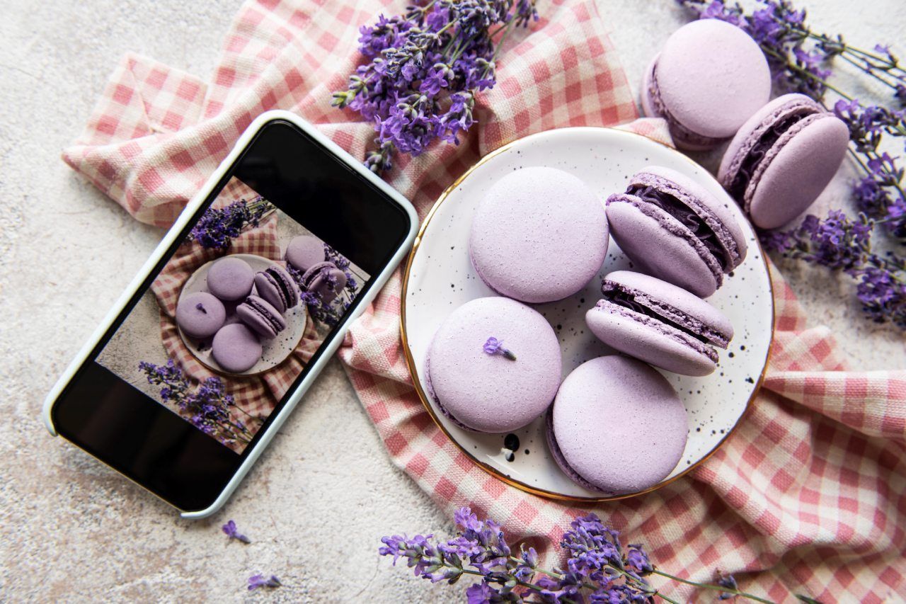 Um celular está tirando uma foto de macarons roxos em um prato.
