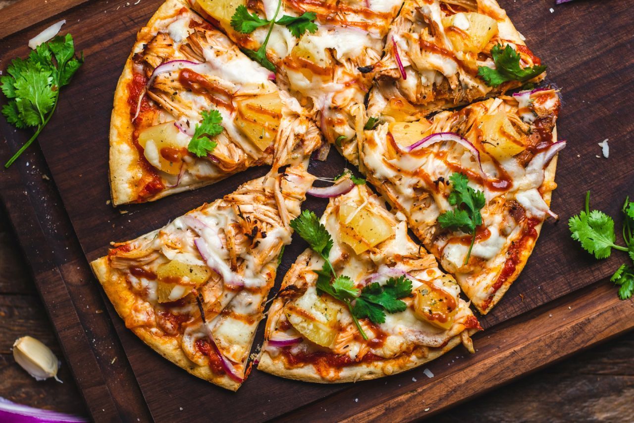 Uma pizza está sobre uma tábua de corte de madeira.