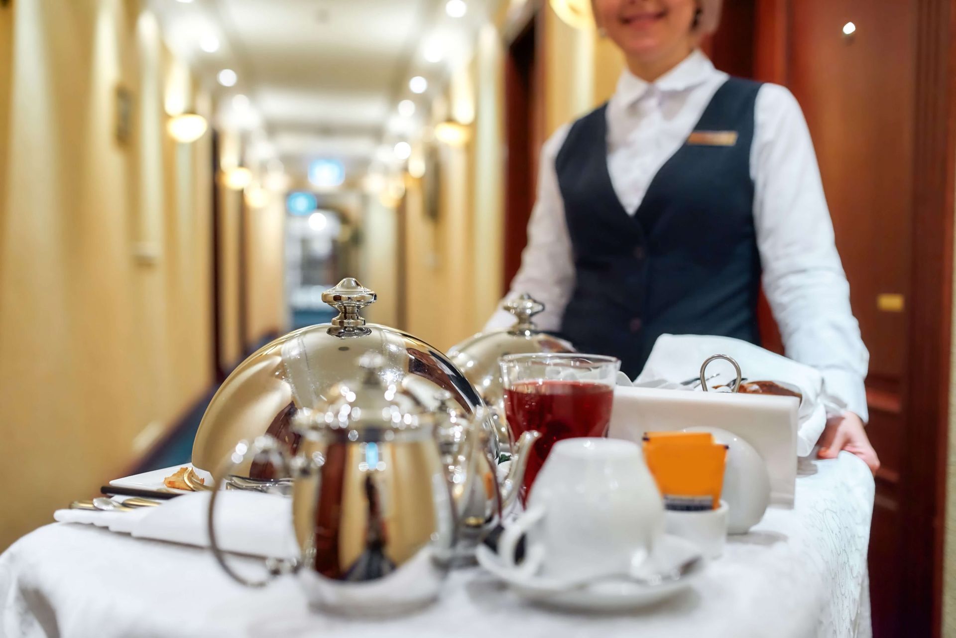 Uma garçonete está carregando uma bandeja de comida no corredor de um hotel.