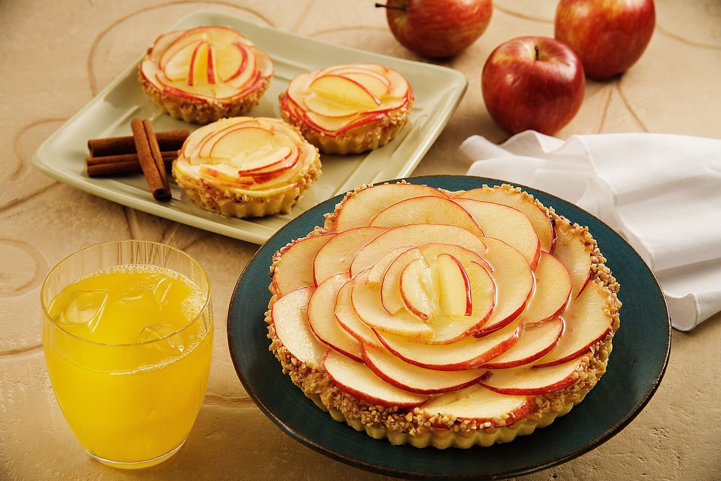 Uma torta de maçã está em um prato ao lado de um copo de suco de laranja.