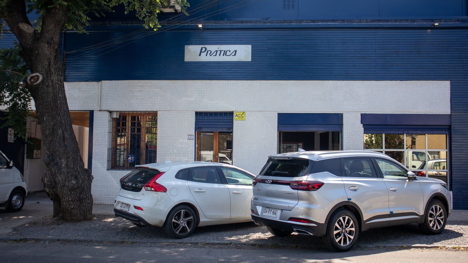 Dois carros estão estacionados em frente a um prédio.