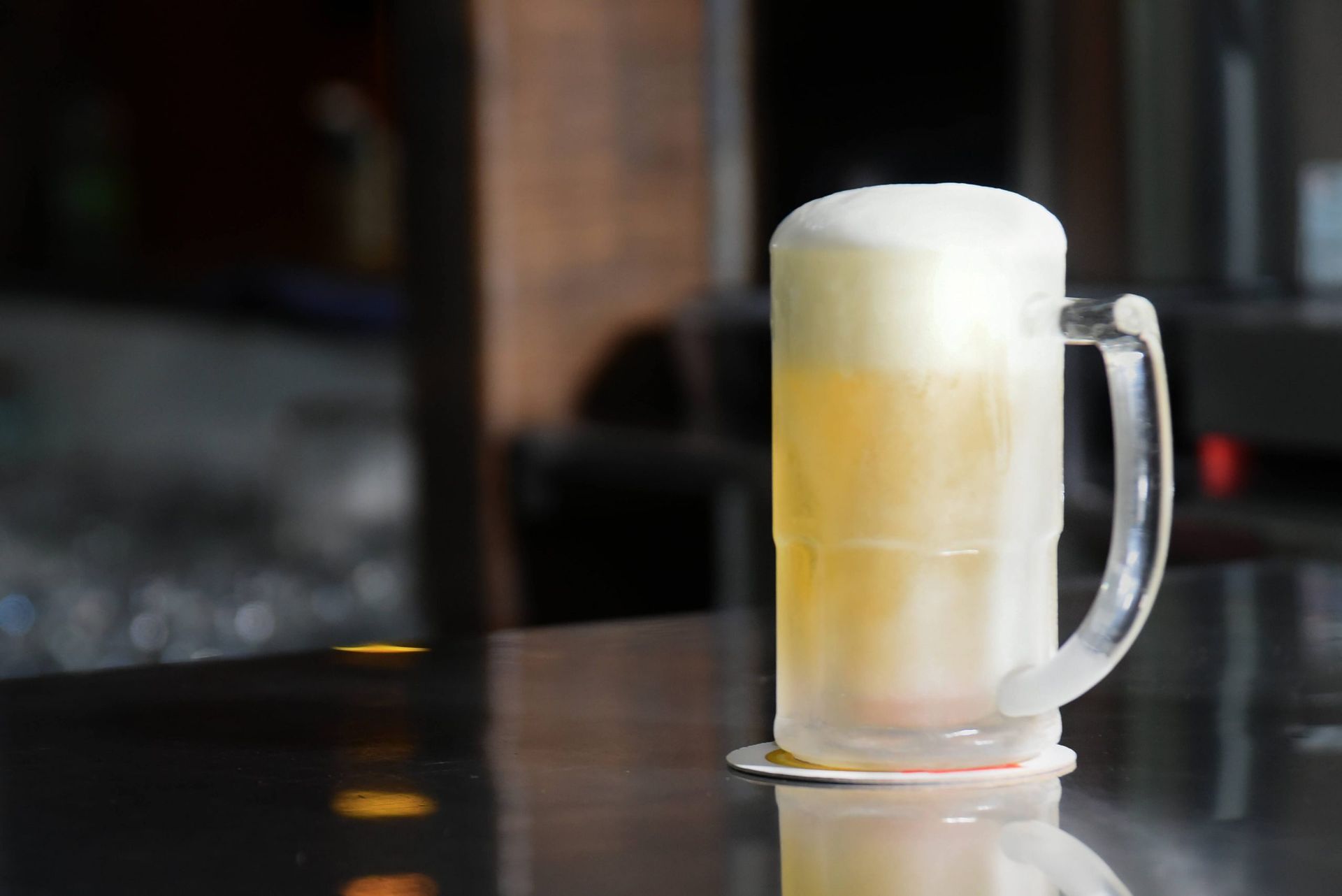 Uma caneca de vidro cheia de cerveja está sobre uma mesa.