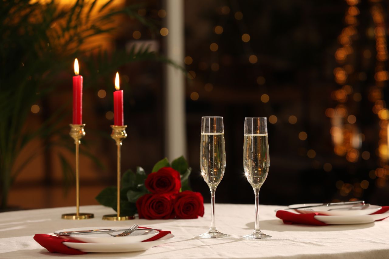 Uma mesa posta para um jantar de dia dos namorados com velas e taças de champanhe.