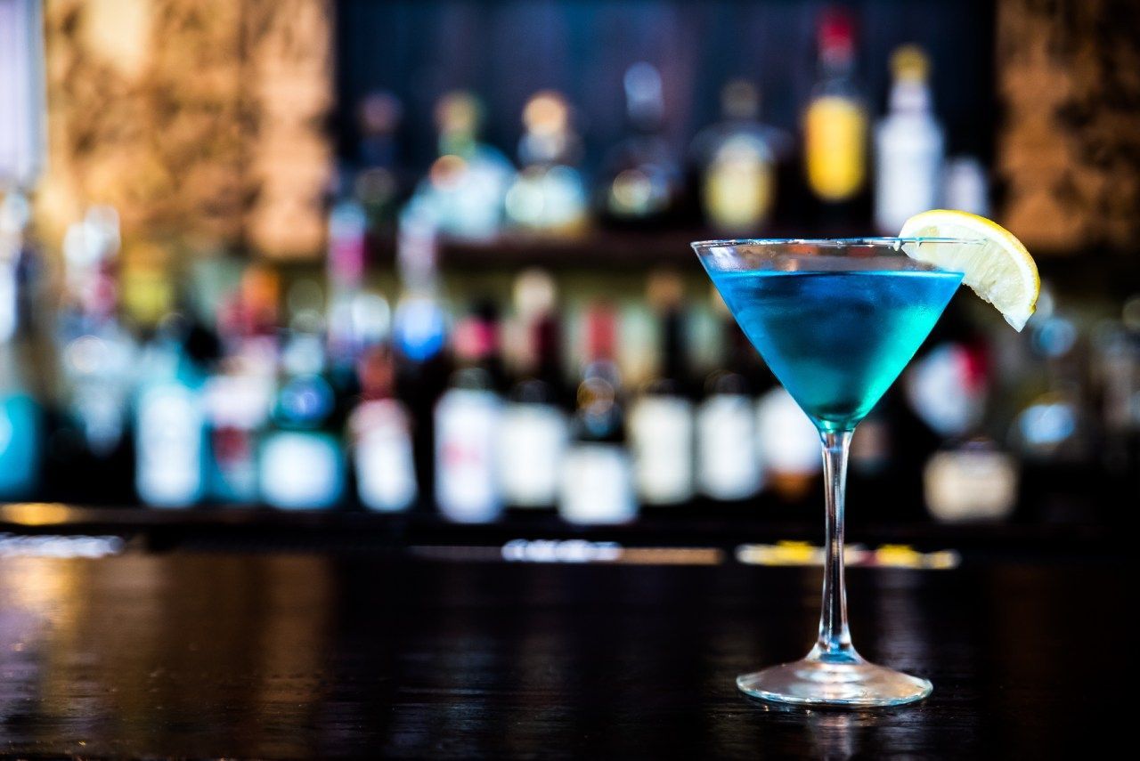 Um blue martini com uma rodela de limão no bar.
