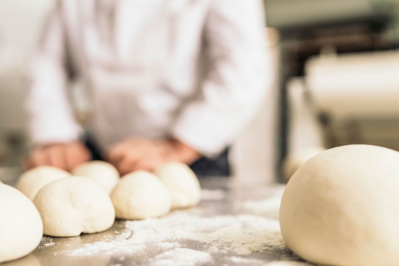 Uma pessoa está amassando massa em uma mesa na cozinha.