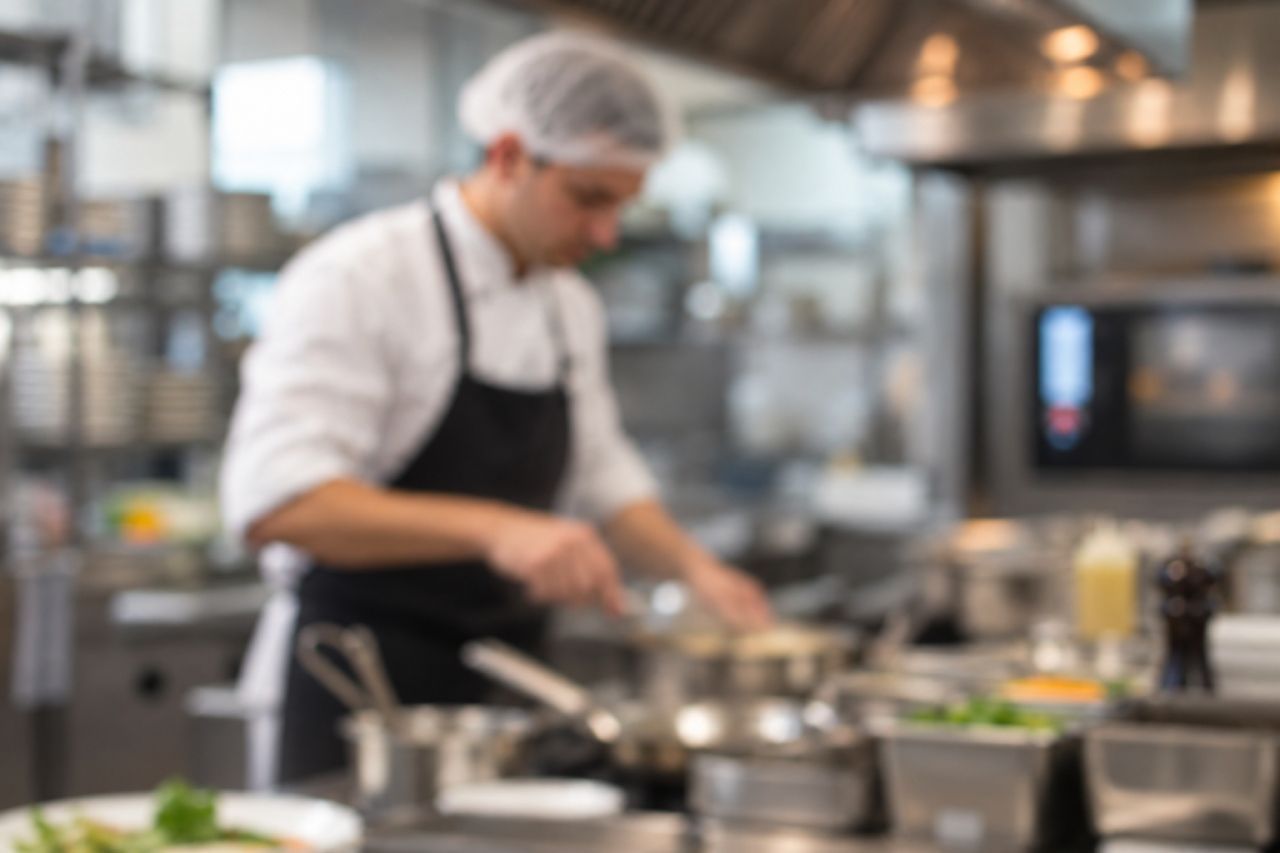 Um chef está preparando comida em uma cozinha.