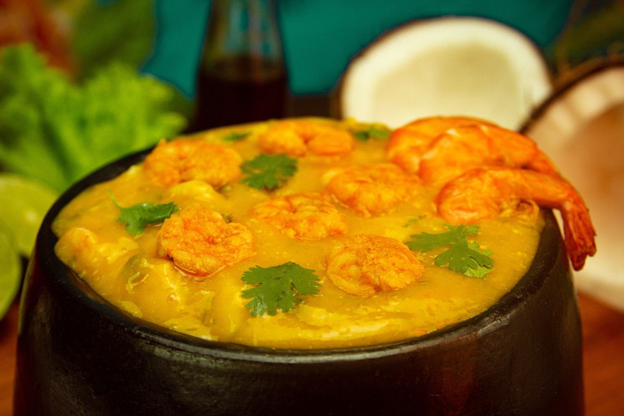 Uma tigela de curry com camarão e coco sobre uma mesa.