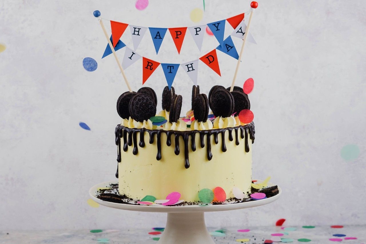 Um bolo de aniversário com uma faixa de feliz aniversário em cima.