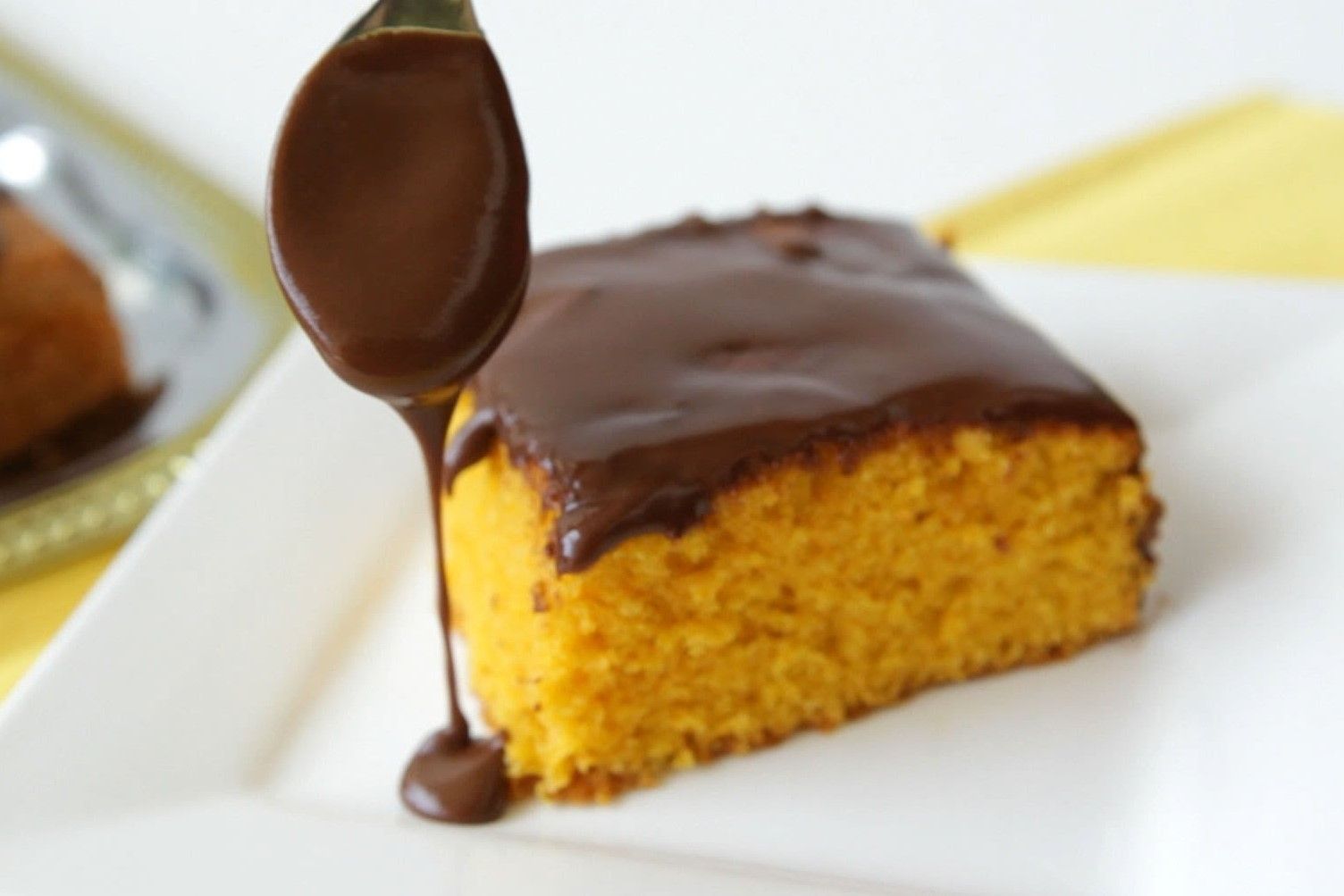 Um pedaço de bolo com cobertura de chocolate sendo derramada sobre ele