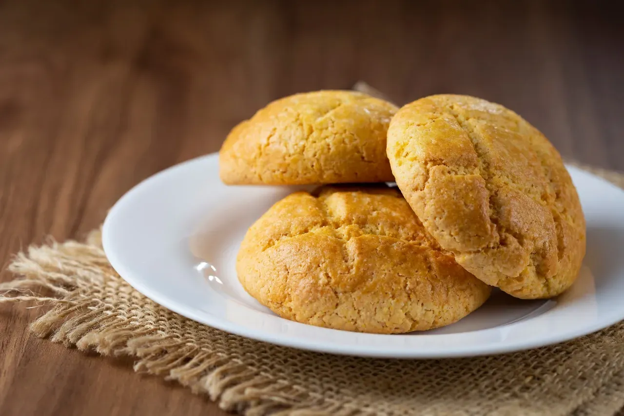 Três biscoitos estão em um prato branco sobre uma mesa de madeira.