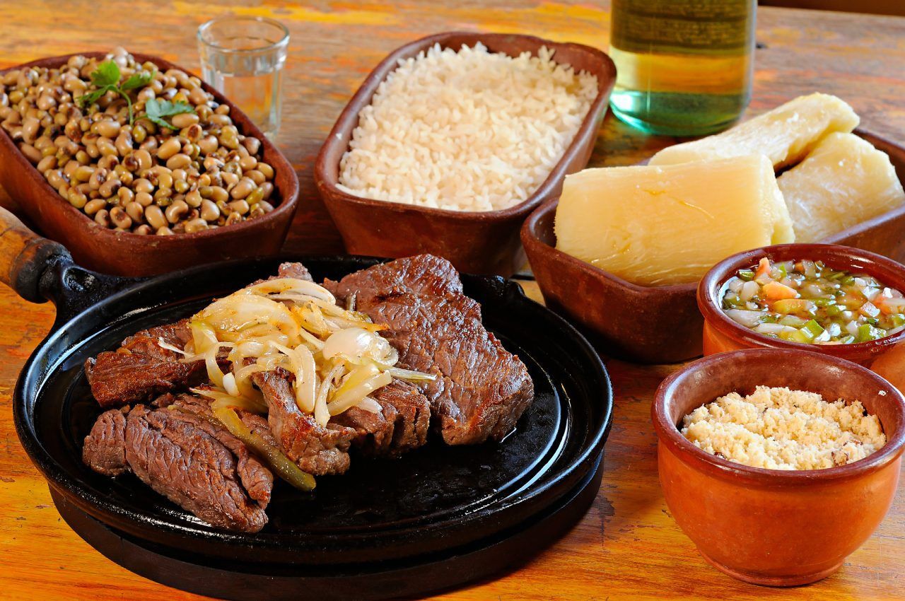 Um prato de comida com carne, arroz e vegetais sobre uma mesa.