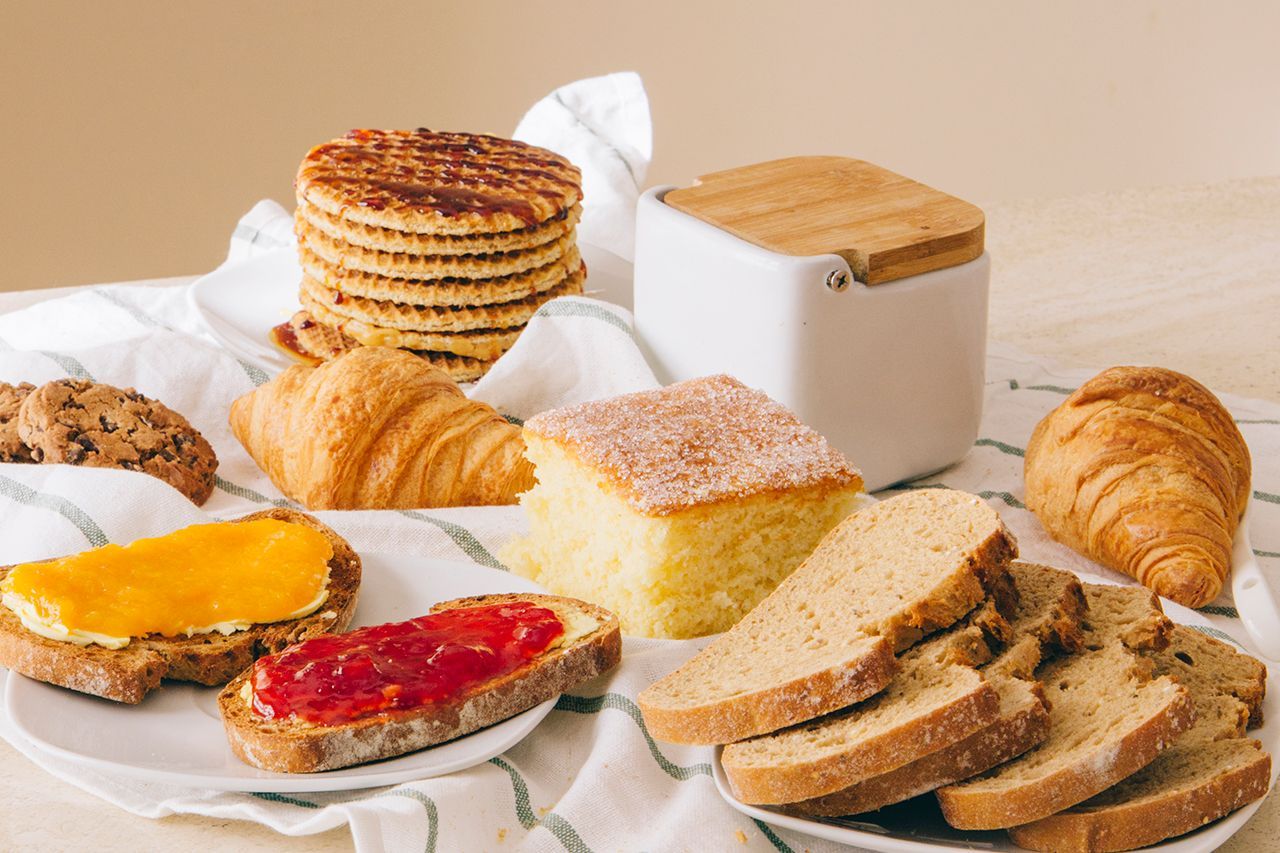 Há muitos tipos diferentes de pães e doces na mesa.