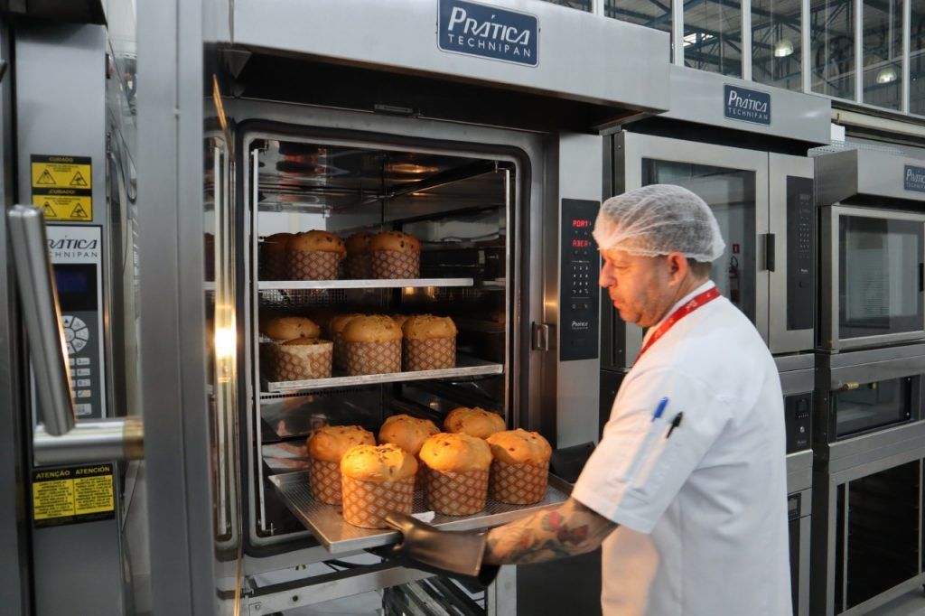 Um homem está tirando uma bandeja de muffins do forno.