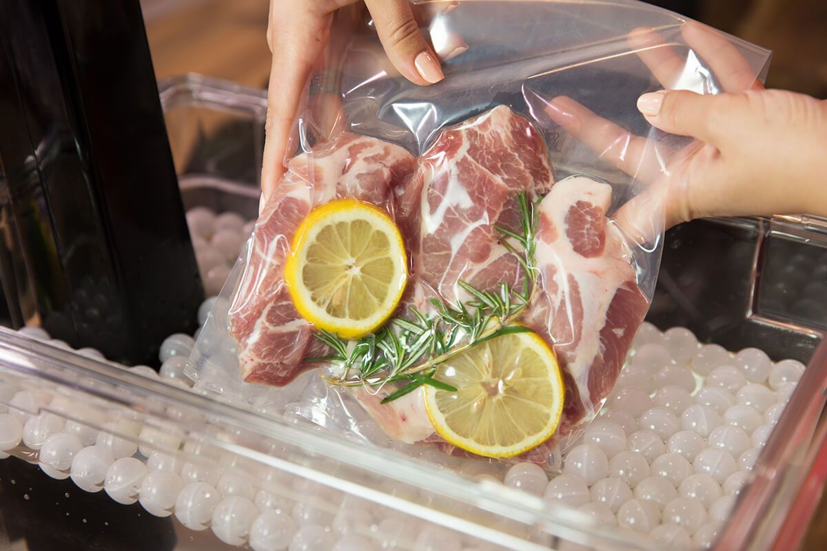 Uma pessoa está colocando carne em um saco plástico com rodelas de limão.