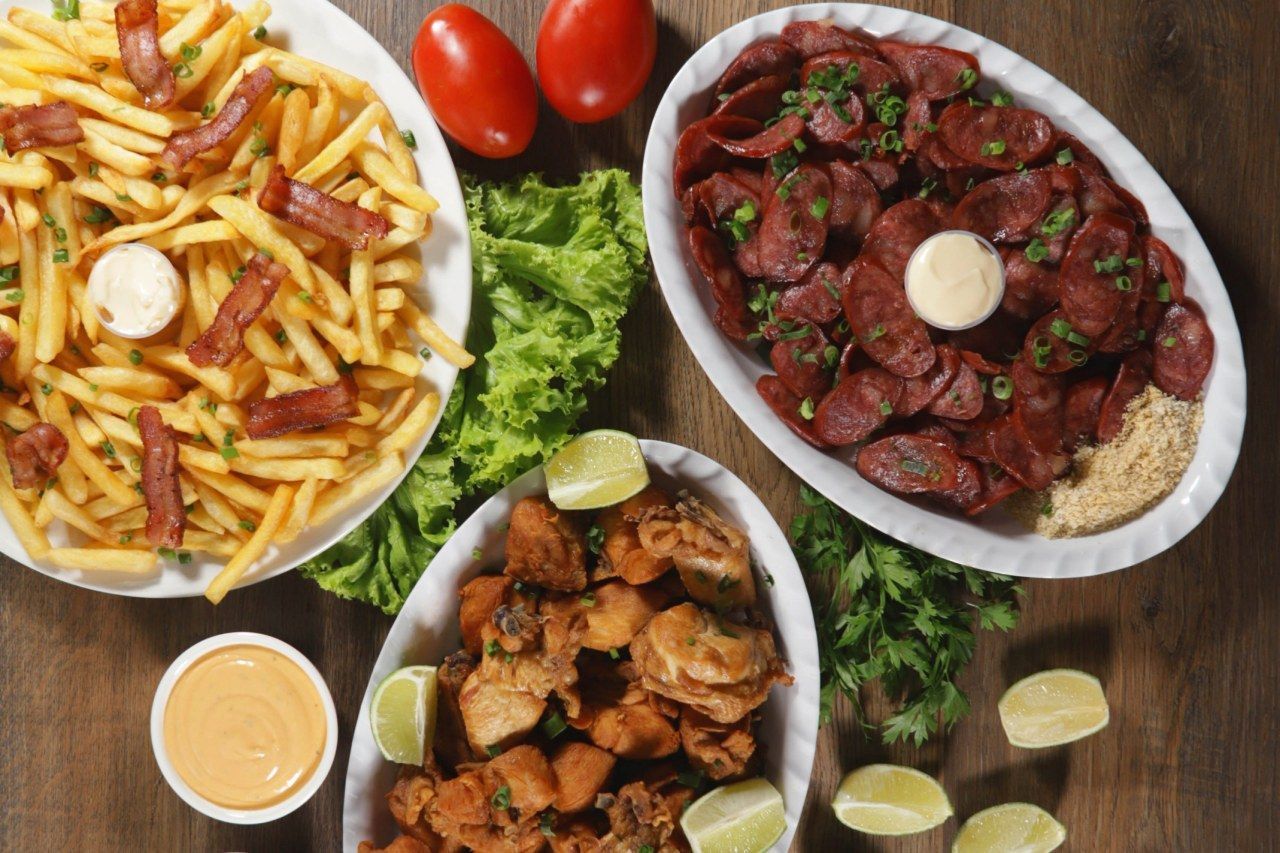 Três pratos de comida estão sobre uma mesa de madeira.