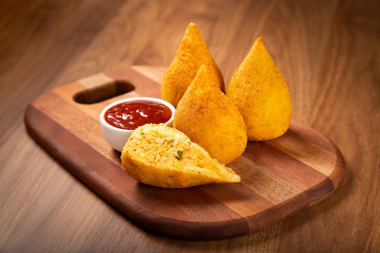 Uma tábua de corte de madeira coberta com alimentos fritos e ketchup.