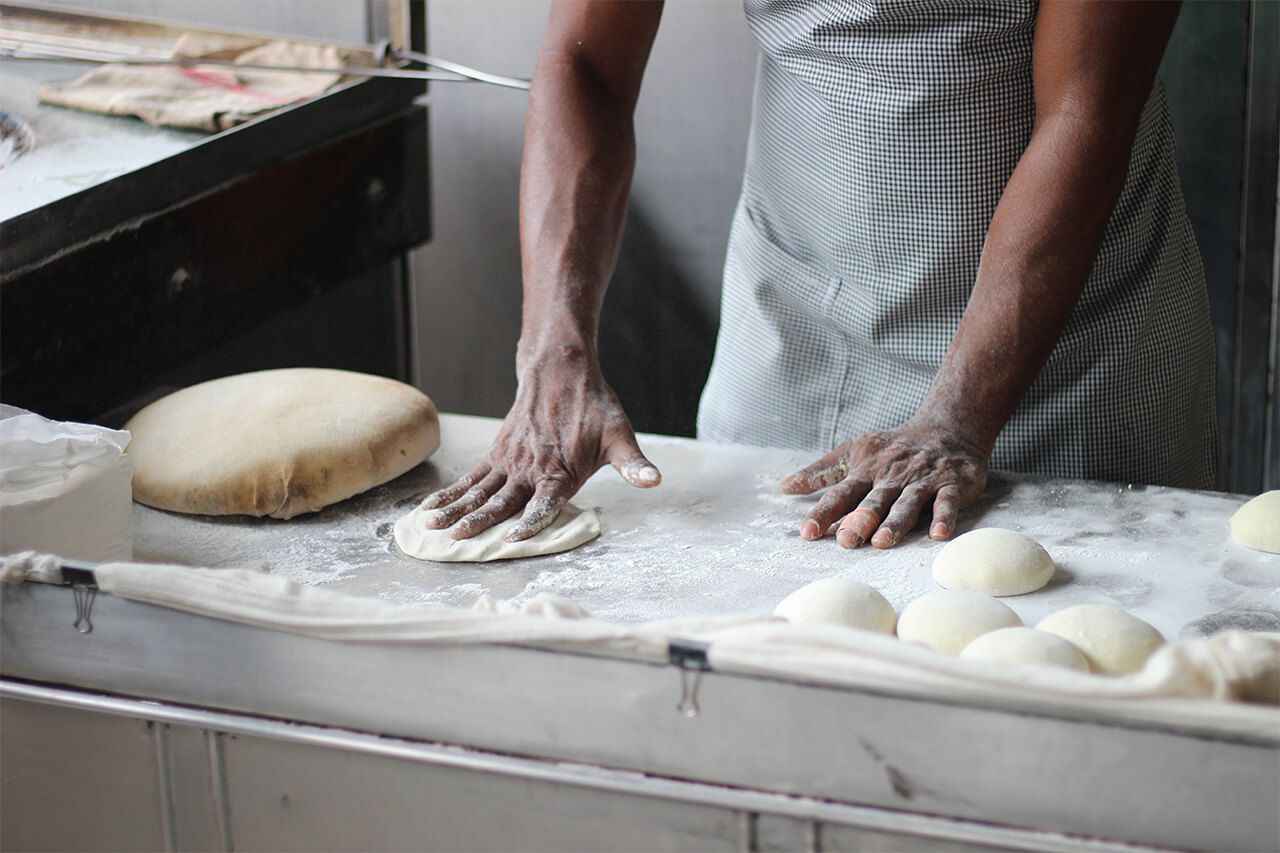 Uma pessoa está amassando massa em um balcão de uma cozinha.