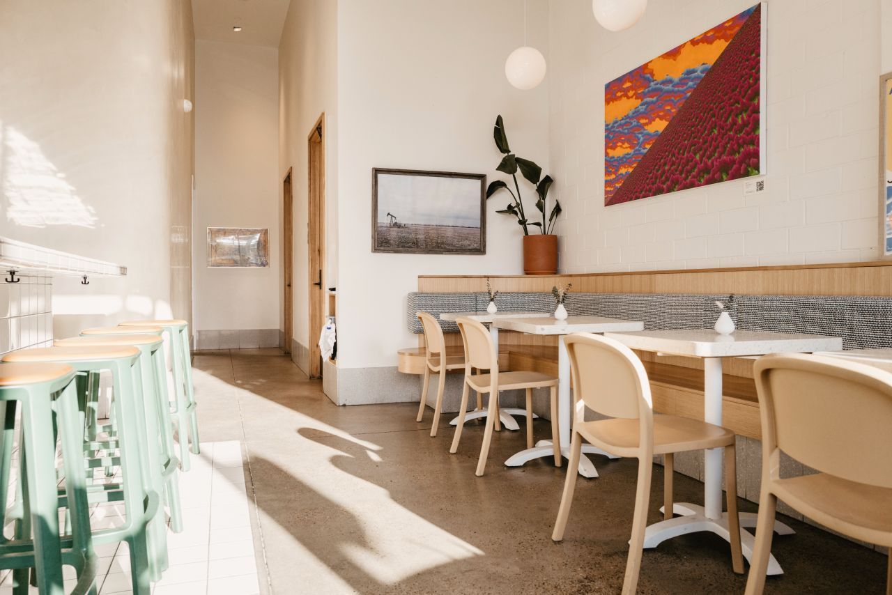 Um restaurante com mesas e cadeiras e uma pintura na parede.