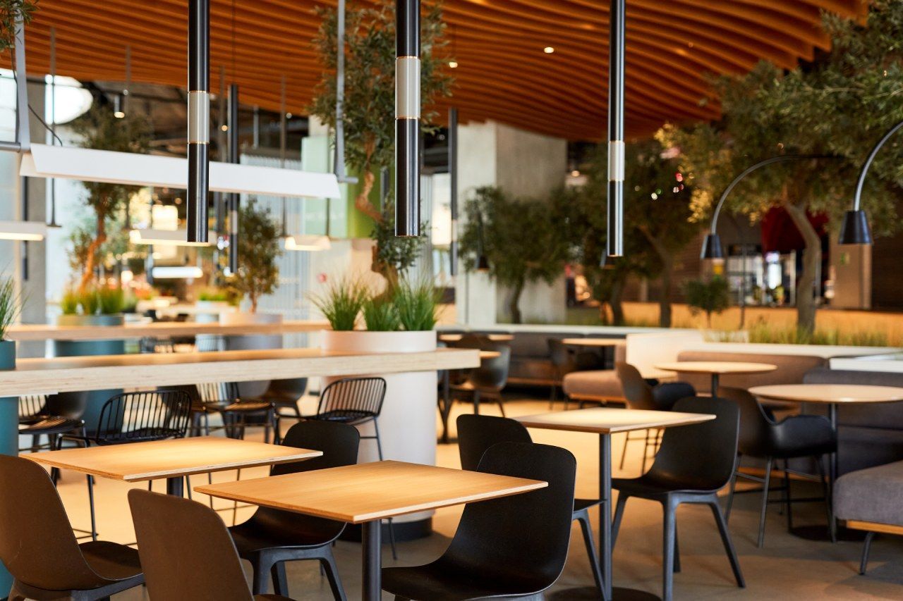 Um restaurante com mesas e cadeiras e um teto de madeira.