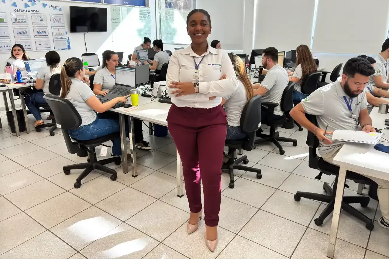 Uma mulher está de pé em um escritório com os braços cruzados.