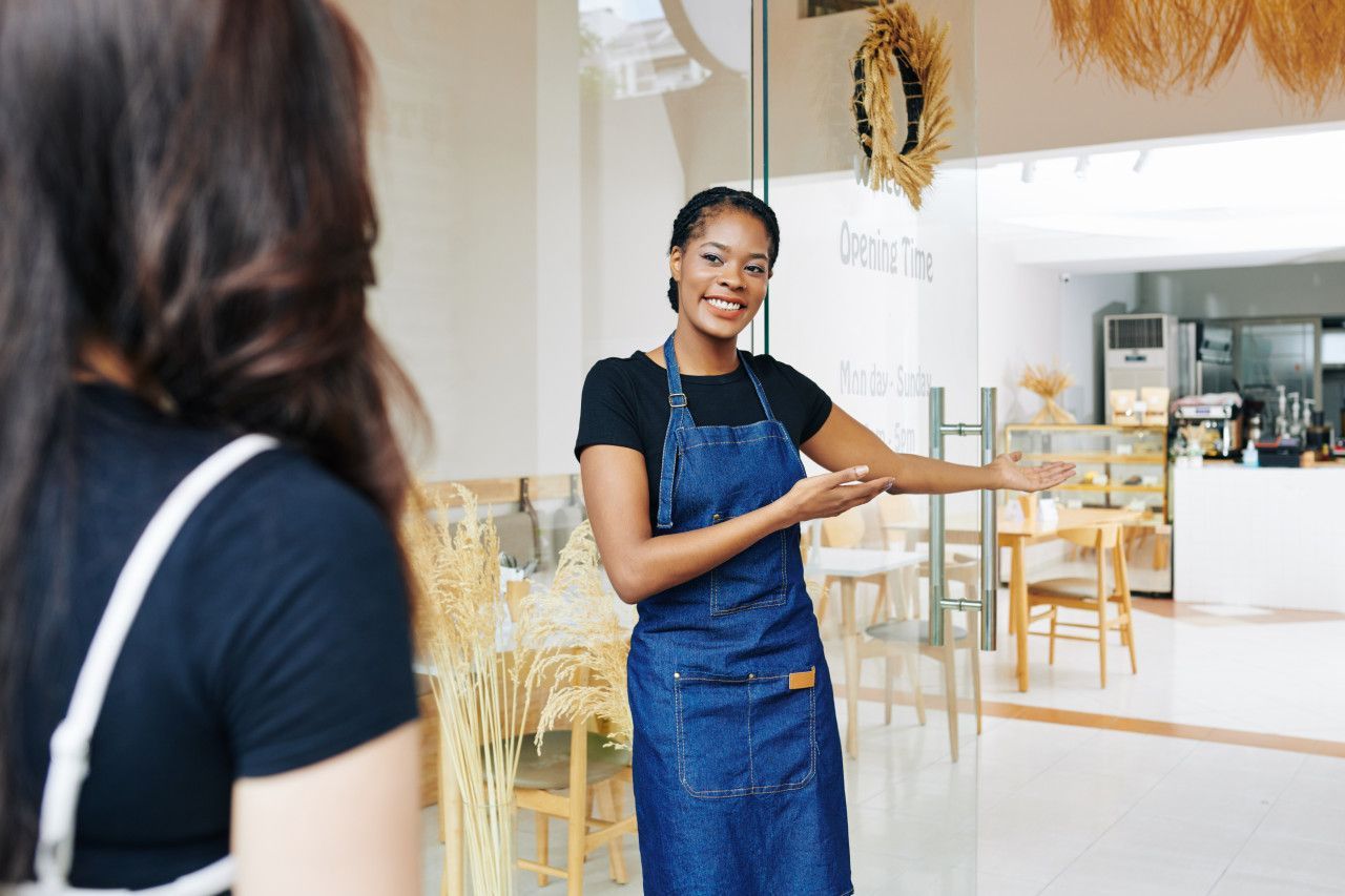 Uma mulher de avental está conversando com outra mulher em um restaurante.