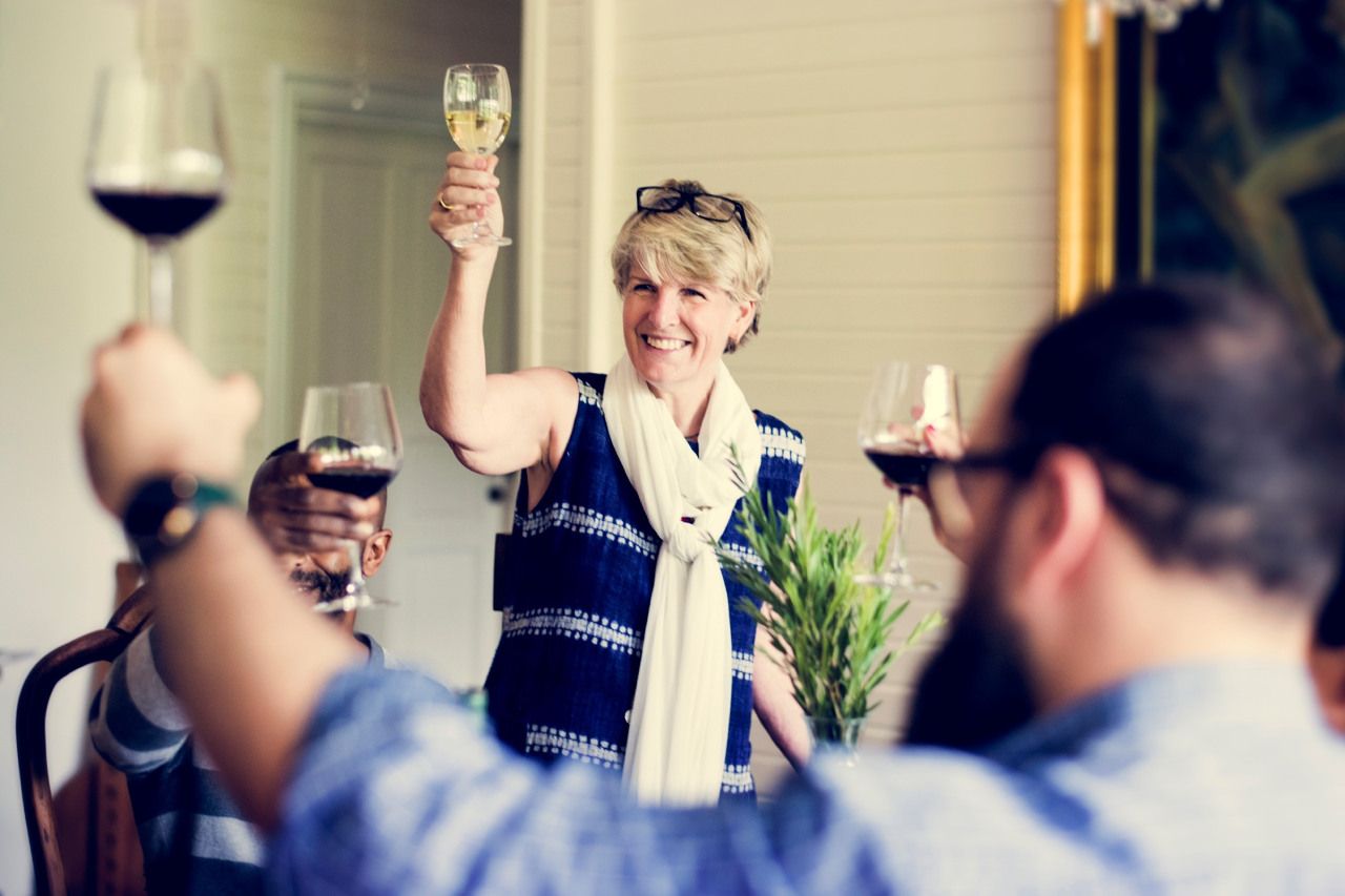Um grupo de pessoas está brindando com taças de vinho em uma festa.
