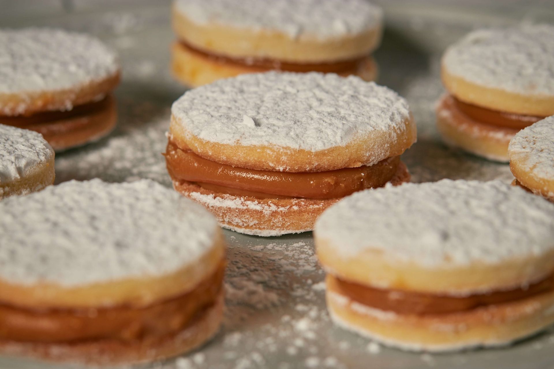 Um monte de biscoitos cobertos com açúcar de confeiteiro sobre uma mesa.