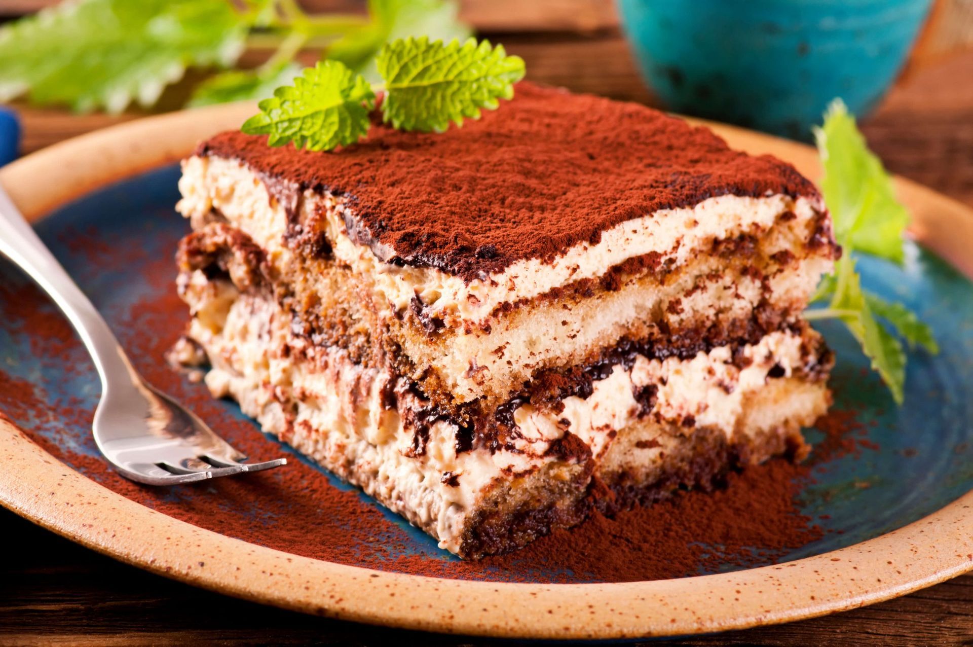 Uma fatia de bolo tiramisu em um prato com um garfo.