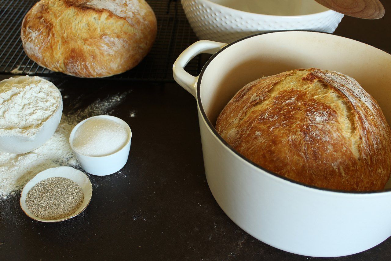 Um pão está em uma panela branca sobre uma mesa