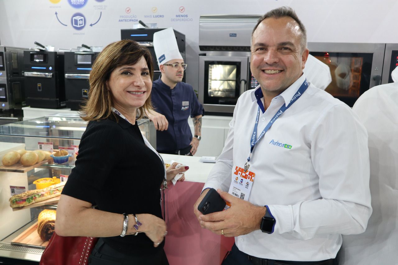 Um homem e uma mulher estão de pé um ao lado do outro e sorrindo.