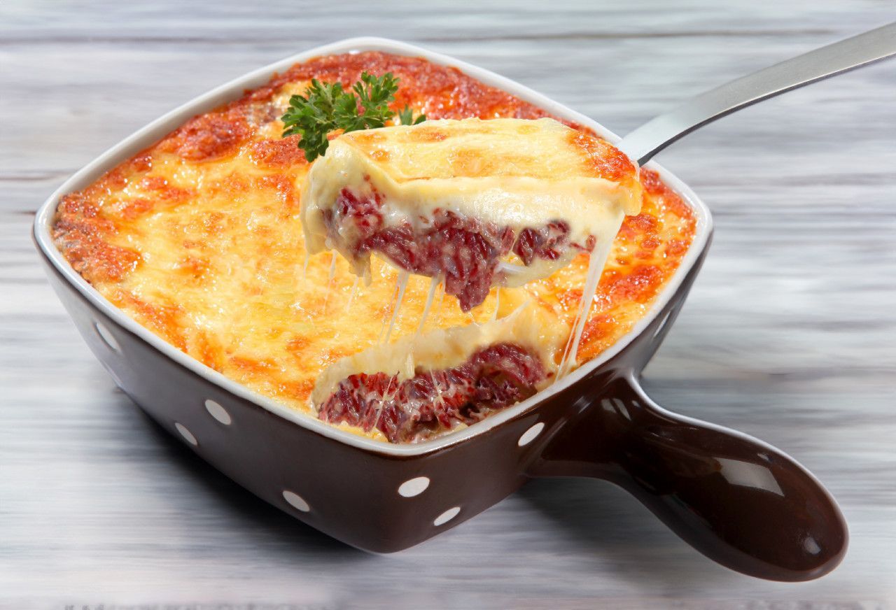 Uma tigela de comida com uma colher dentro sobre uma mesa.