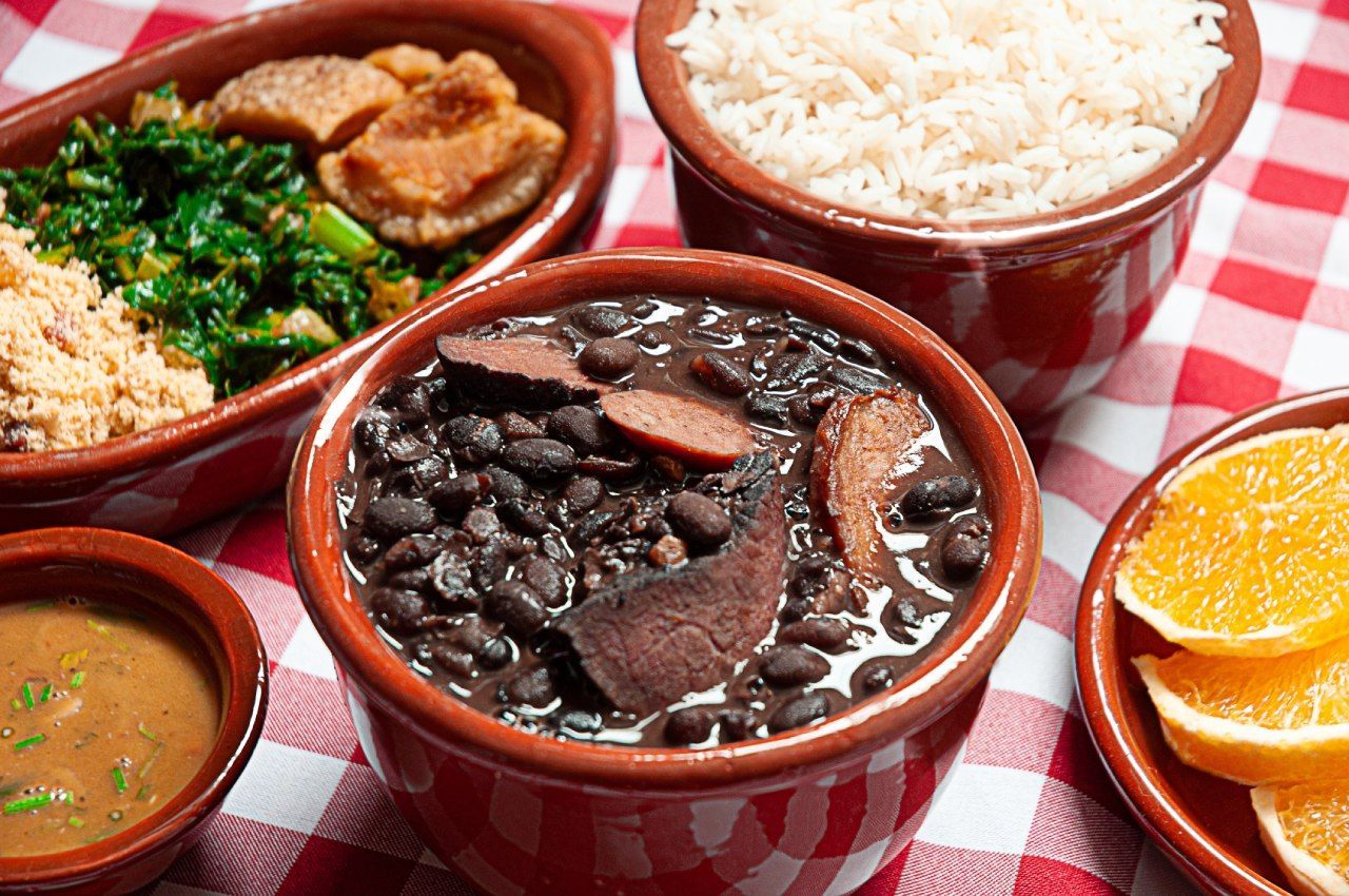 Uma mesa coberta com tigelas de comida, incluindo feijão, arroz e laranjas.