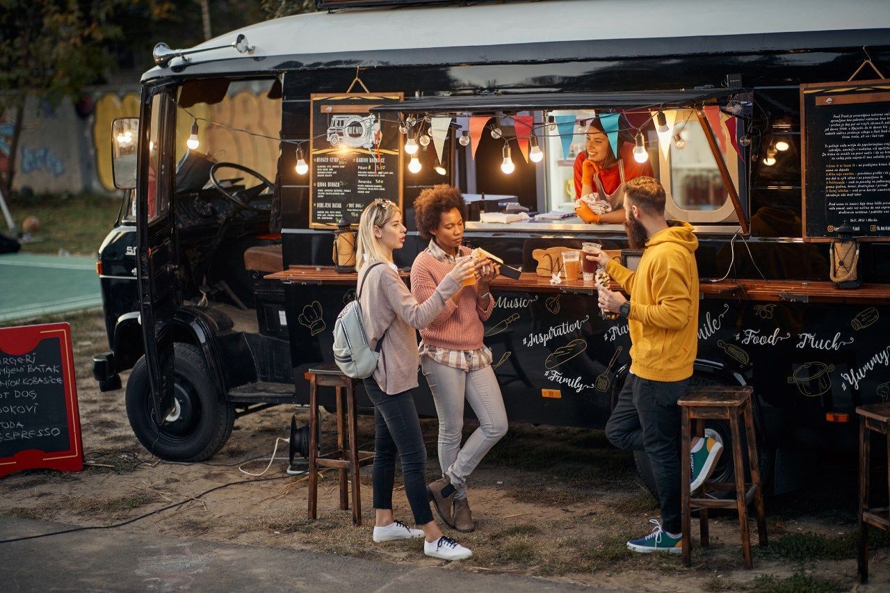 Um grupo de pessoas está em frente a um food truck.